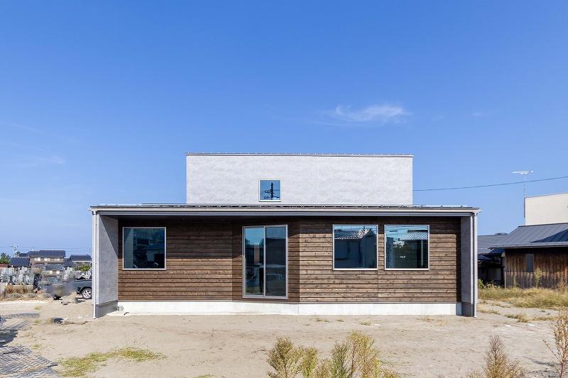 淡いグレーの外壁に横ばりの無垢板がアクセント。