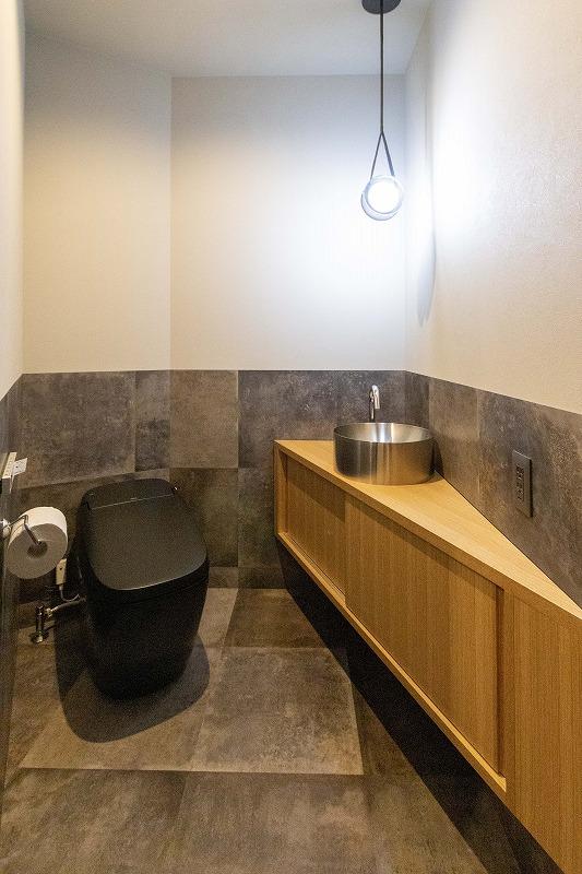 トイレ。斜めに作った手洗いと収納。腰壁にも床材をはって統一感を。